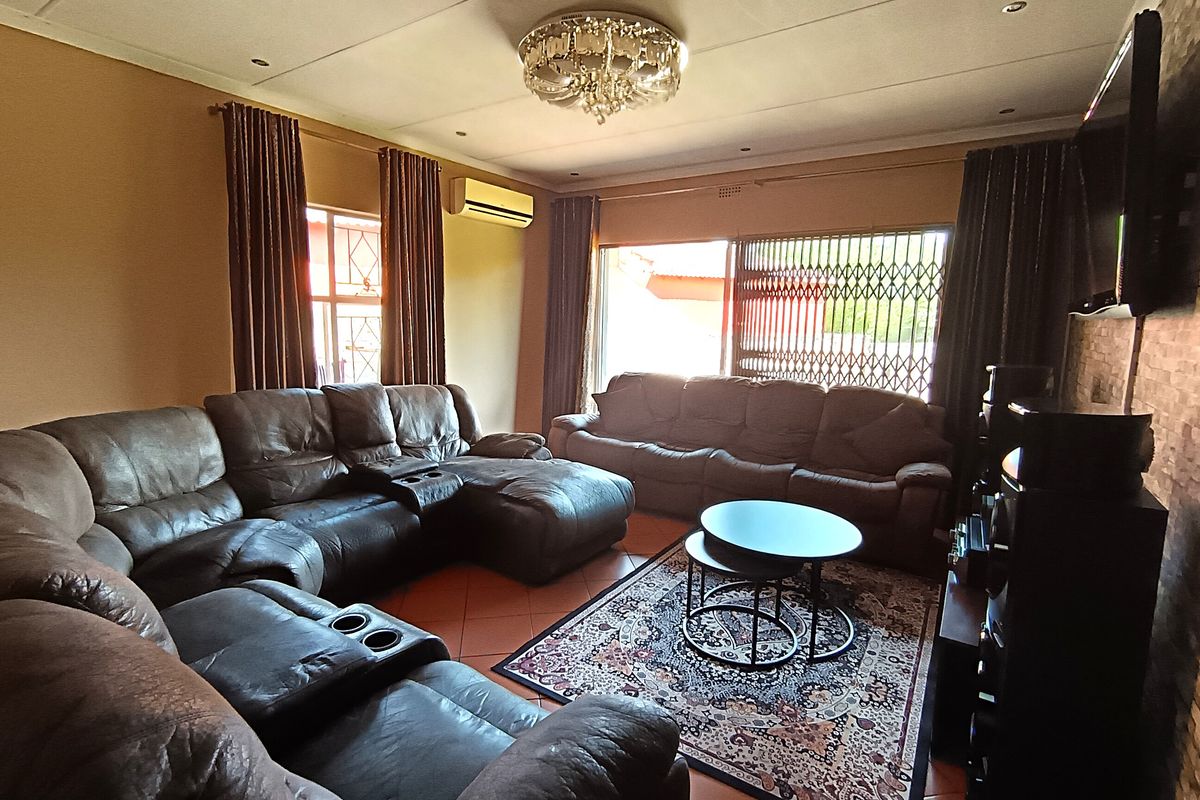 A comfortable living room featuring tiled flooring, a textured feature wall, split-system air conditioning, and direct access to the exterior through a sliding glass door.