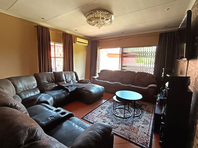 A comfortable living room featuring tiled flooring, a textured feature wall, split-system air conditioning, and direct access to the exterior through a sliding glass door.