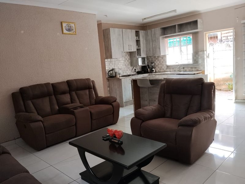 Open-plan living area featuring a modern kitchen with built-in cabinetry, breakfast counter, and tiled flooring throughout the space.