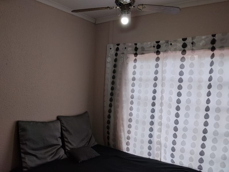 A bedroom featuring a ceiling fan and neutral wall finishes, providing a functional space for rest.