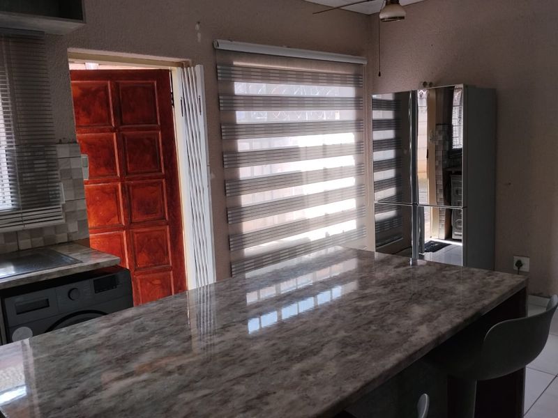 A functional kitchen area featuring a marble-effect island countertop, built-in laundry appliance, and direct access to an exterior door.