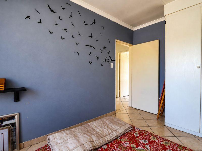 A bedroom featuring tiled flooring, a built-in wardrobe, and blue accent wall with decorative decals.