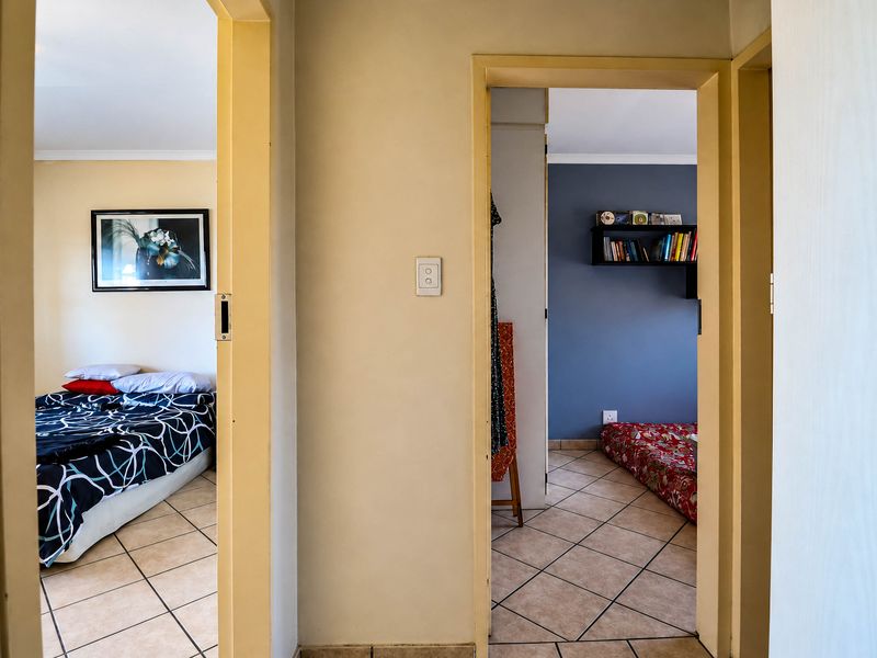 A central hallway providing access to two bedrooms, featuring neutral wall tones and tiled flooring throughout.