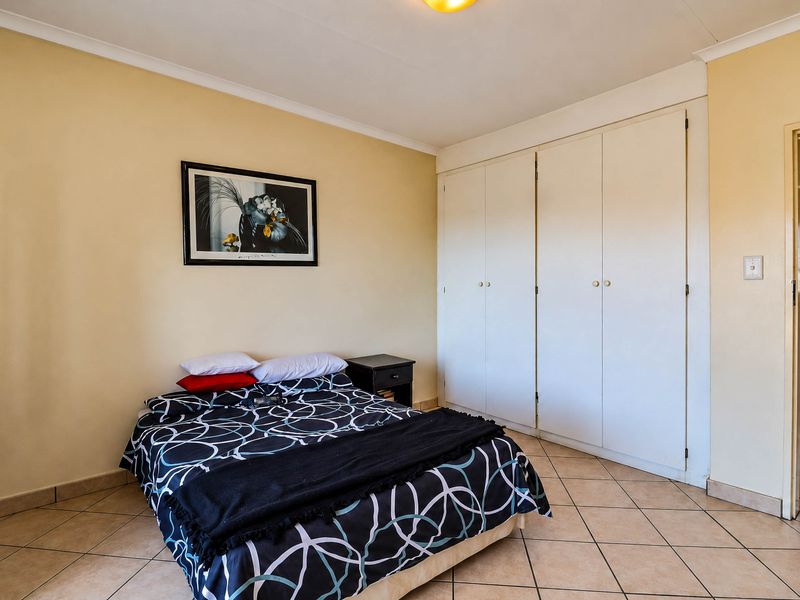A bedroom featuring tiled flooring, coved ceilings, and ample built-in cupboard storage space.