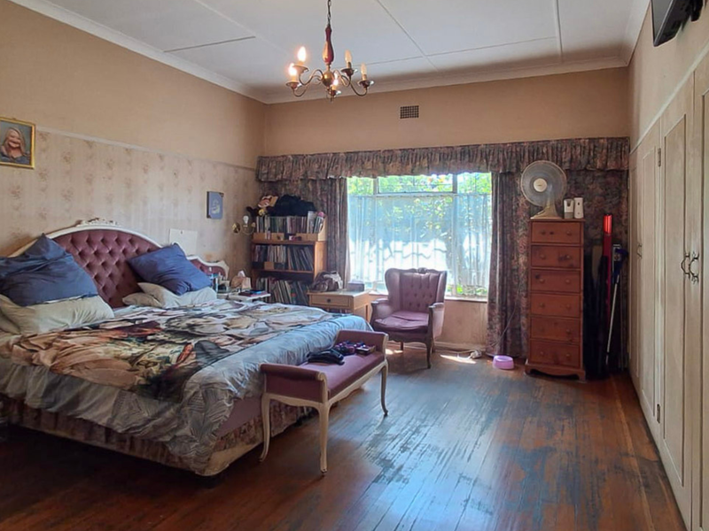 Spacious bedroom featuring original timber flooring, built-in cupboards, and classic picture rails, offering a traditional layout with potential for modern updates.