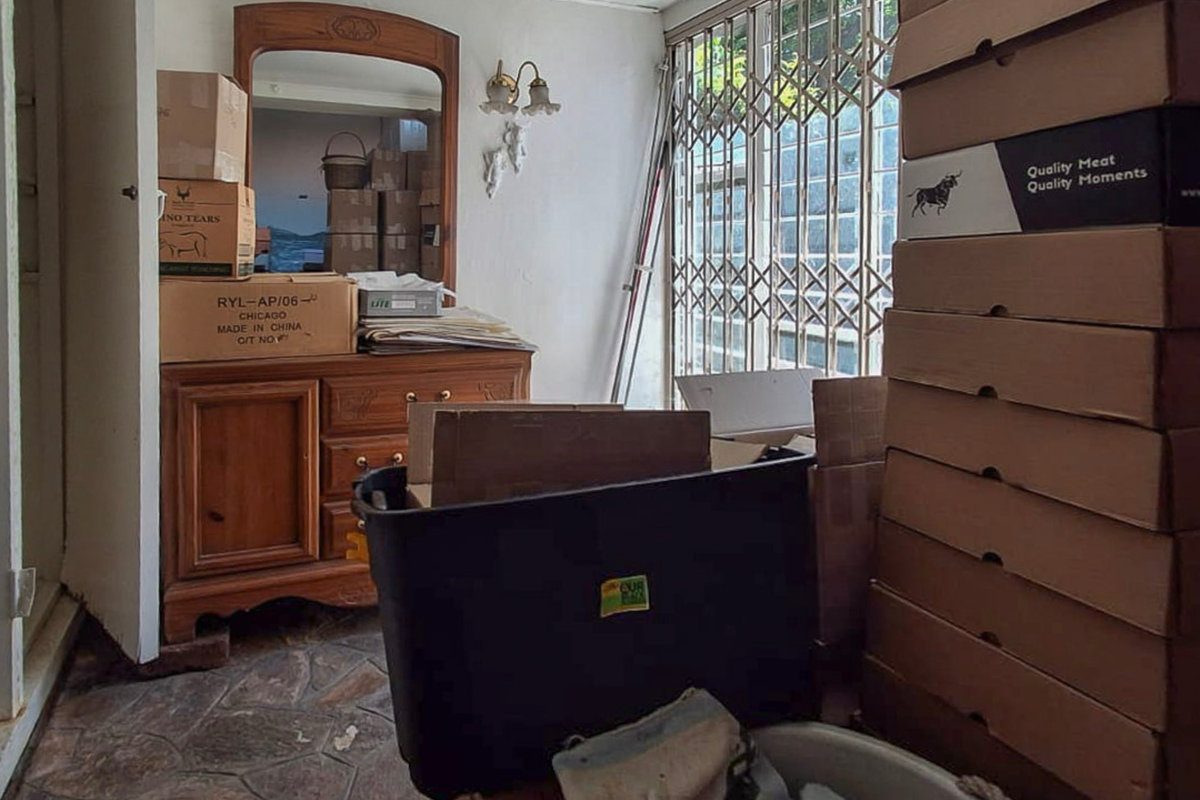 A living area featuring tiled flooring and a security gate, currently used for storage.