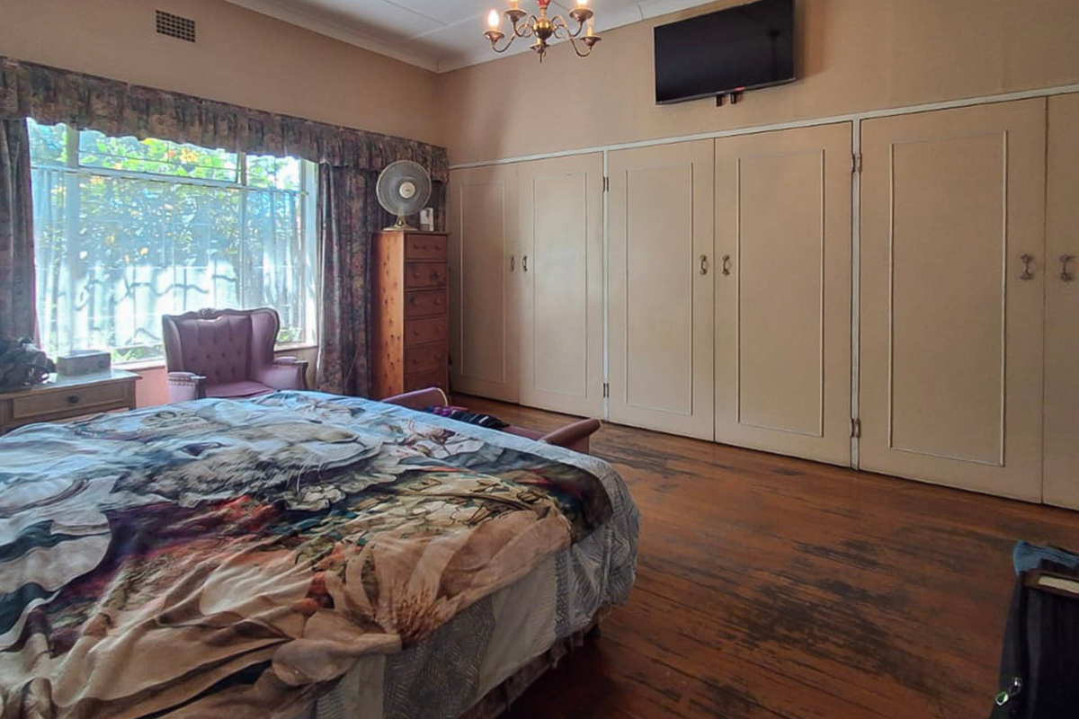 Spacious bedroom featuring extensive built-in cupboards and original hardwood flooring, offering a classic layout with potential for modern updates.