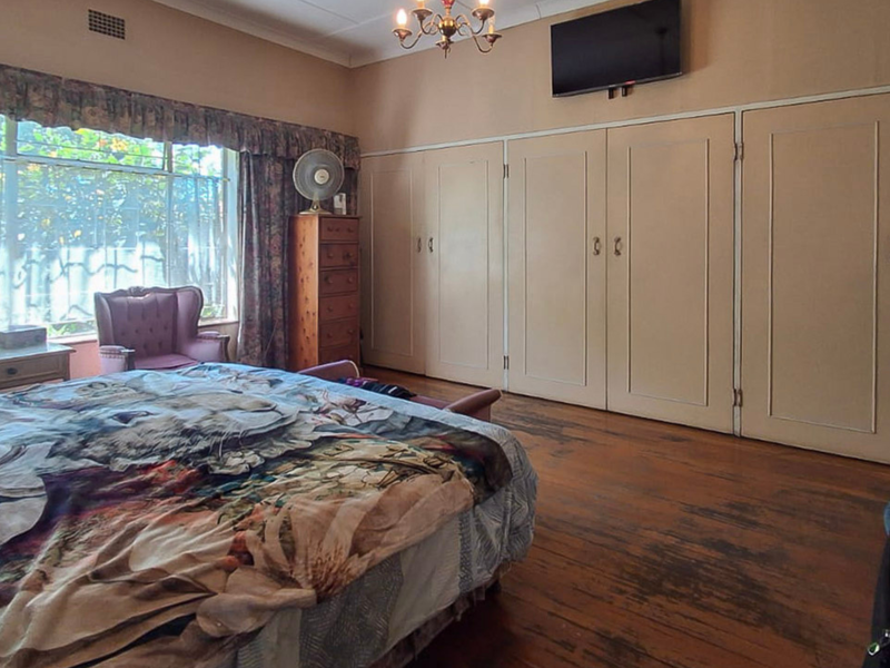 Spacious bedroom featuring extensive built-in cupboards and original hardwood flooring, offering a classic layout with potential for modern updates.