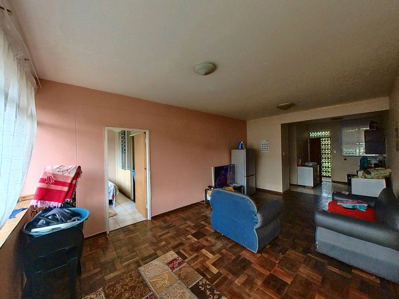 Open-plan living area featuring parquet flooring and direct access to adjacent rooms, offering a functional layout with potential for cosmetic updates.