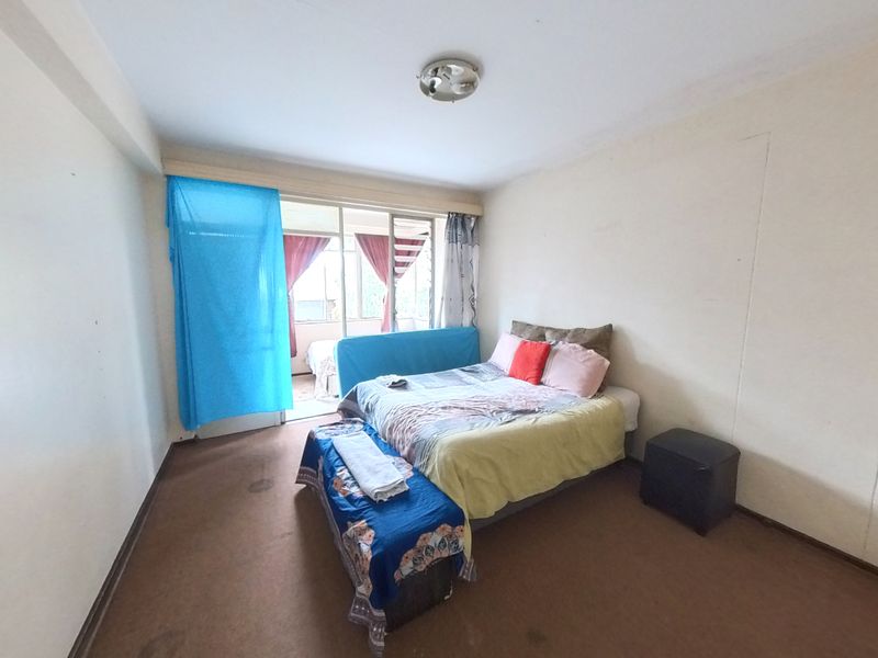 A bedroom featuring carpeted flooring and a sliding glass door providing access to an adjoining balcony area.