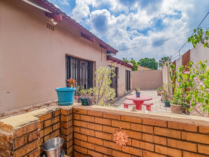 A private rear courtyard featuring paved flooring, a low brick boundary wall, and direct access to the home through security-fitted sliding doors.