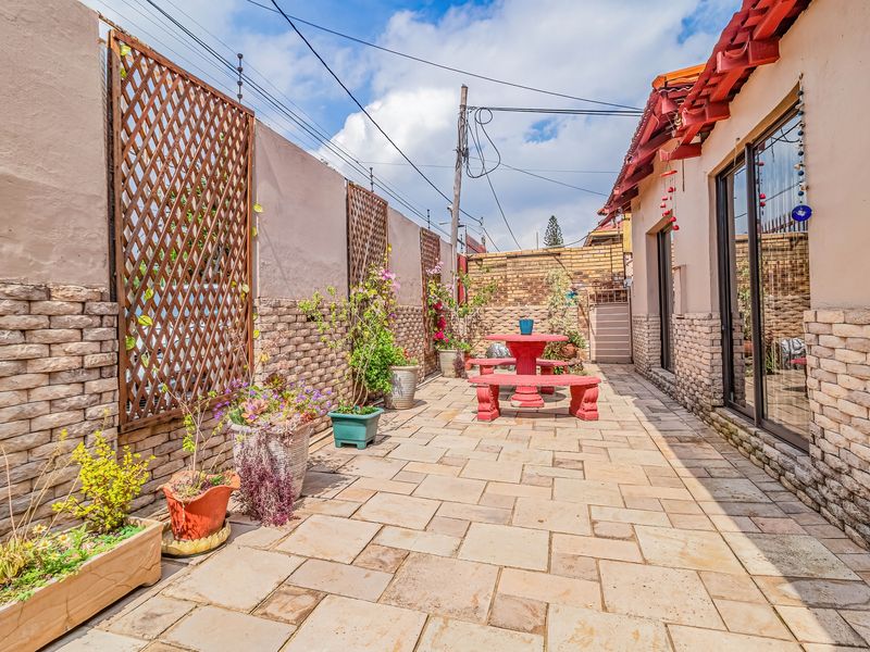 A paved outdoor patio area featuring stone-clad walls, decorative trellis panels, and sliding glass door access to the main dwelling.