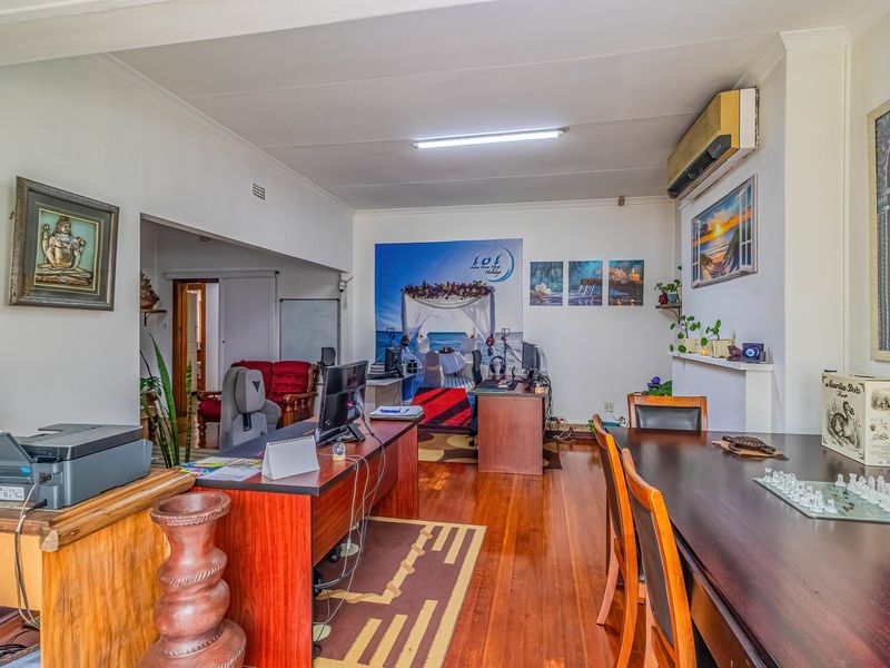 Spacious open-plan living area featuring polished hardwood flooring, coving, and a wall-mounted split-system air conditioner.