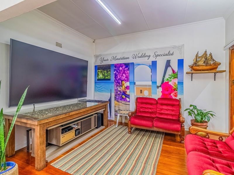 A living room featuring hardwood flooring and a central fluorescent light fixture, providing a functional space for relaxation.