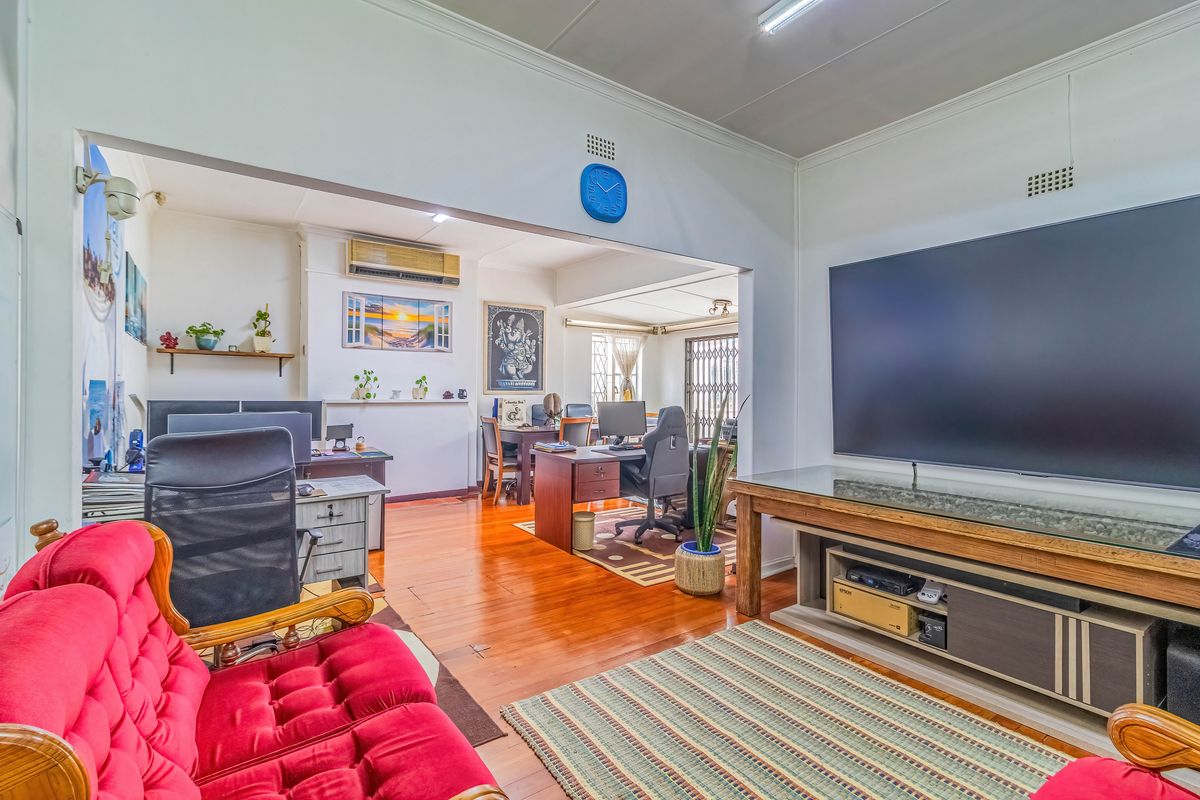 Spacious living area featuring polished hardwood flooring and an open-plan layout connecting to a secondary workspace or study area.
