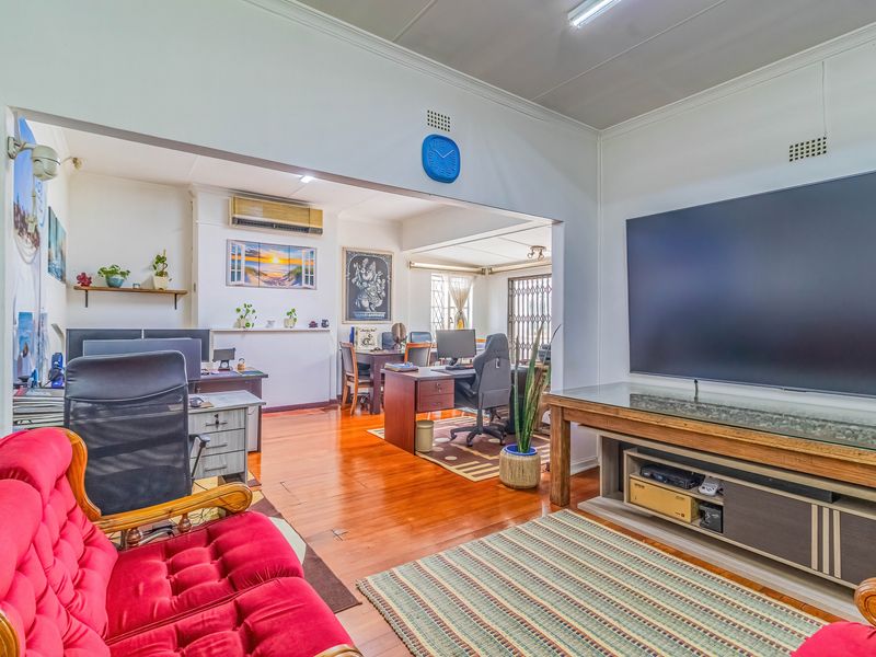 Spacious living area featuring polished hardwood flooring and an open-plan layout connecting to a secondary workspace or study area.