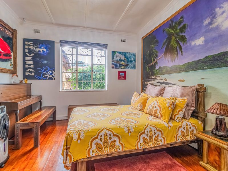 A bedroom featuring polished hardwood flooring, a window with security bars, and ceiling ventilation, providing a functional and well-lit sleeping space.
