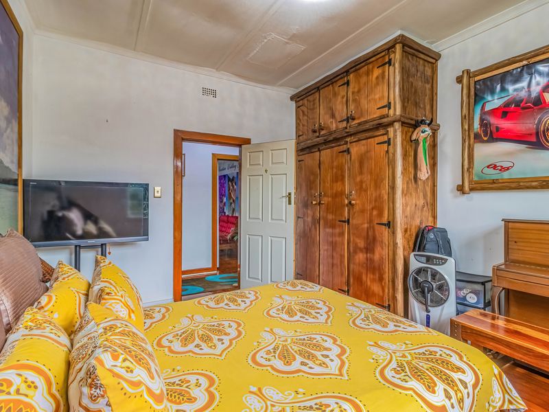 A bedroom featuring a large built-in wooden wardrobe and a wooden door, showing signs of wear on the ceiling and door frame.