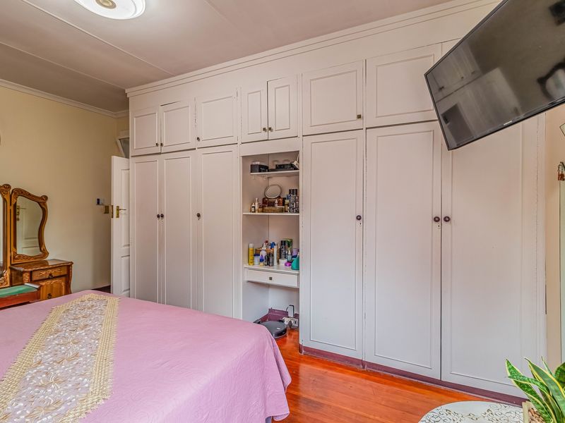 A bedroom featuring extensive floor-to-ceiling built-in cupboards and polished hardwood flooring, providing ample storage space.