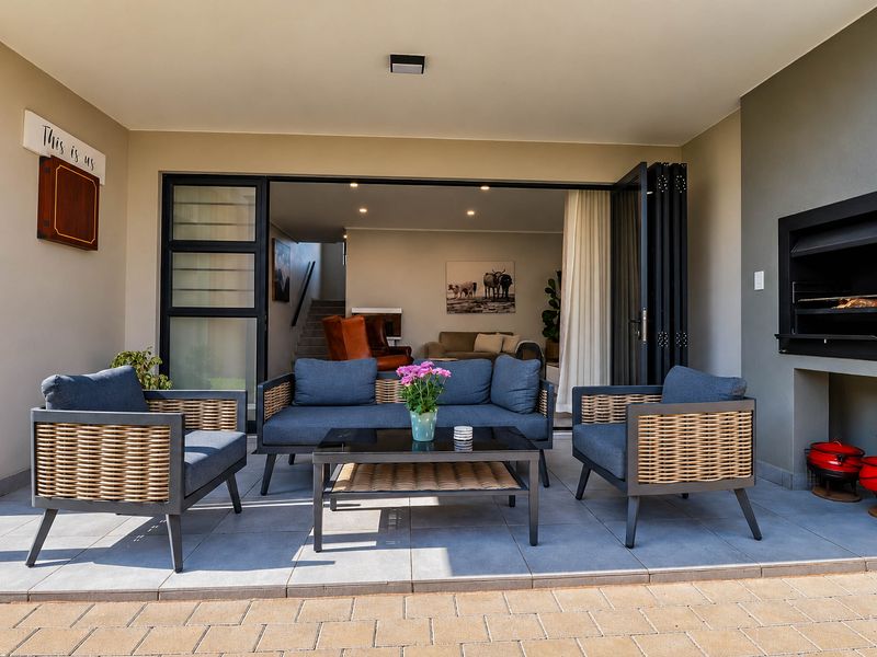 A covered patio featuring tiled flooring, a built-in braai, and seamless access to the interior living area through large stacking doors.