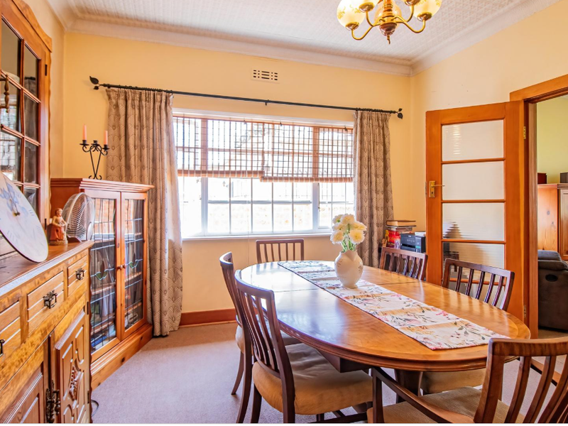 A traditional dining room featuring timber-framed glass doors, decorative ceiling cornices, and built-in cabinetry, offering a warm and classic aesthetic.