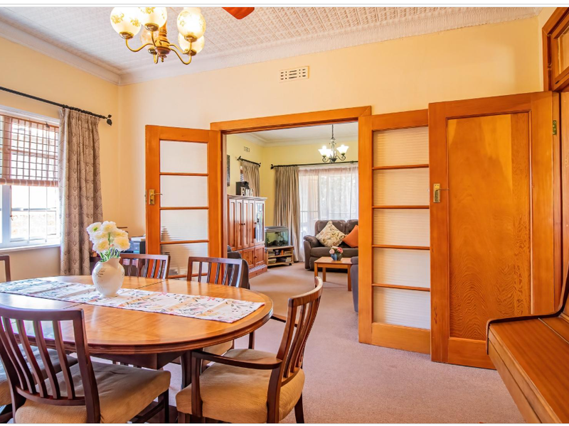 Dining room featuring classic pressed metal ceilings and timber sliding doors connecting to the adjacent living area.
