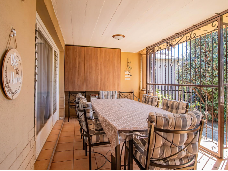 A covered patio area featuring tiled flooring, built-in cabinetry, and a secure wrought iron enclosure, providing a functional outdoor entertainment space.