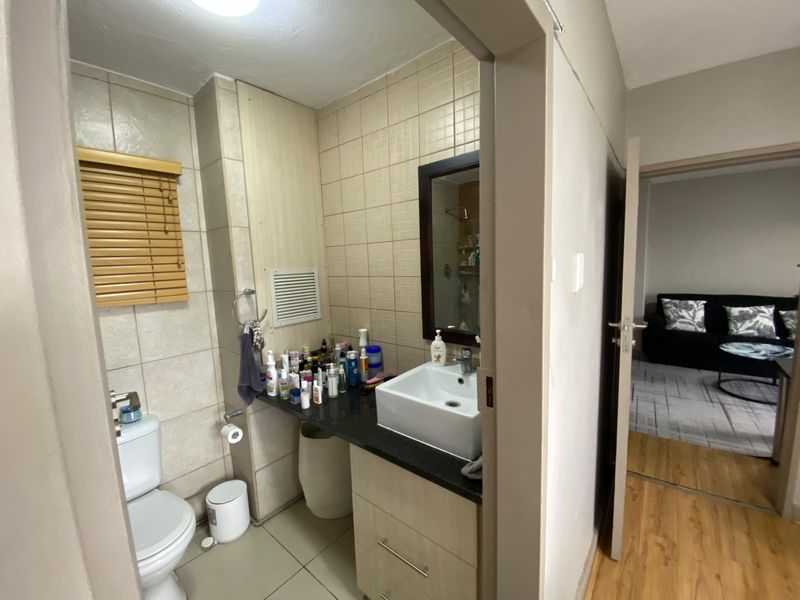 A functional bathroom featuring a vessel sink on a vanity cabinet, tiled walls, and a toilet, with a view into the adjacent living area.
