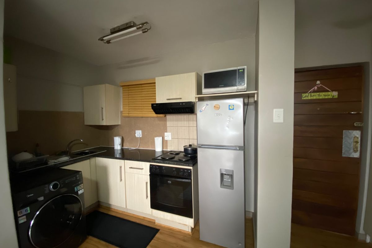 Compact kitchen featuring built-in cabinetry, laminate countertops, integrated oven and hob, and wood-look laminate flooring, providing a functional and efficient workspace.
