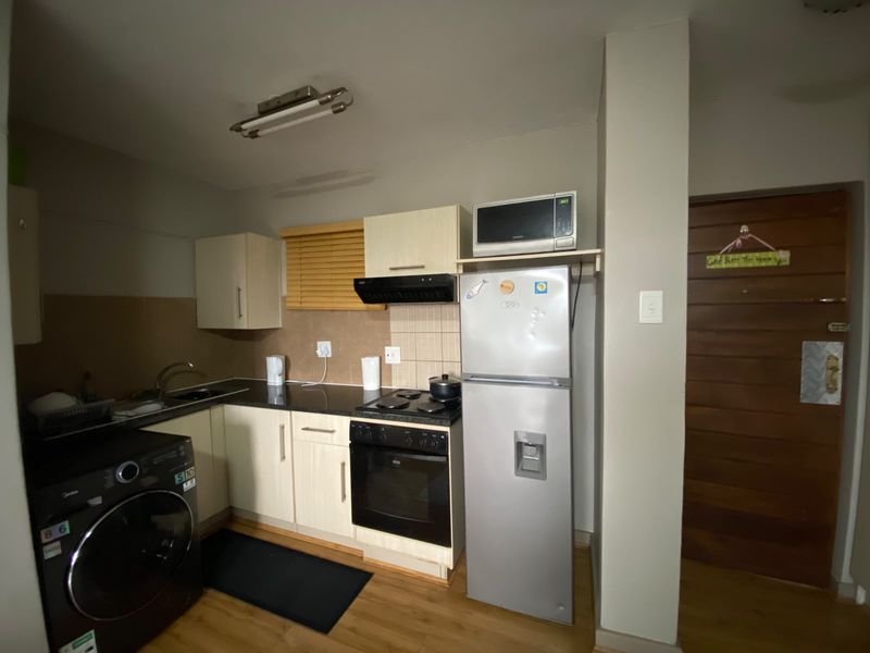 Compact kitchen featuring built-in cabinetry, laminate countertops, integrated oven and hob, and wood-look laminate flooring, providing a functional and efficient workspace.