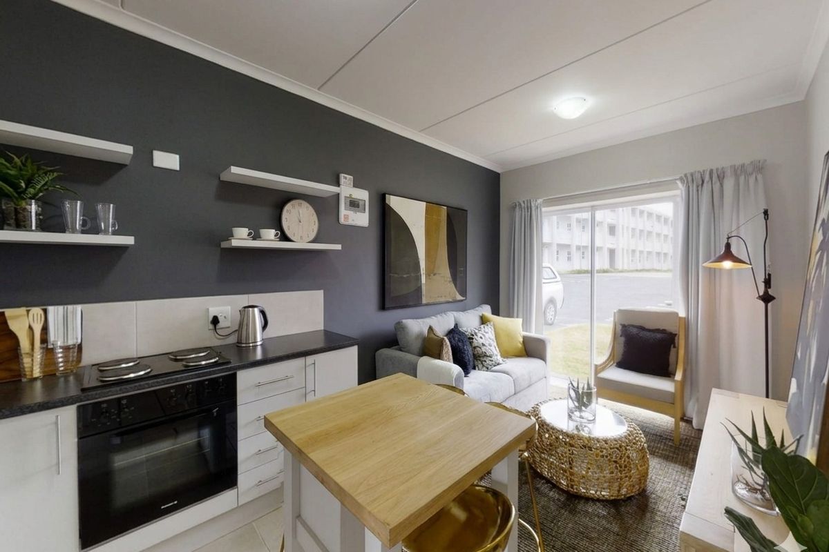 Modern open-plan living area featuring a compact kitchen with built-in oven, hob, and cabinetry, seamlessly flowing into a bright lounge with sliding door access.