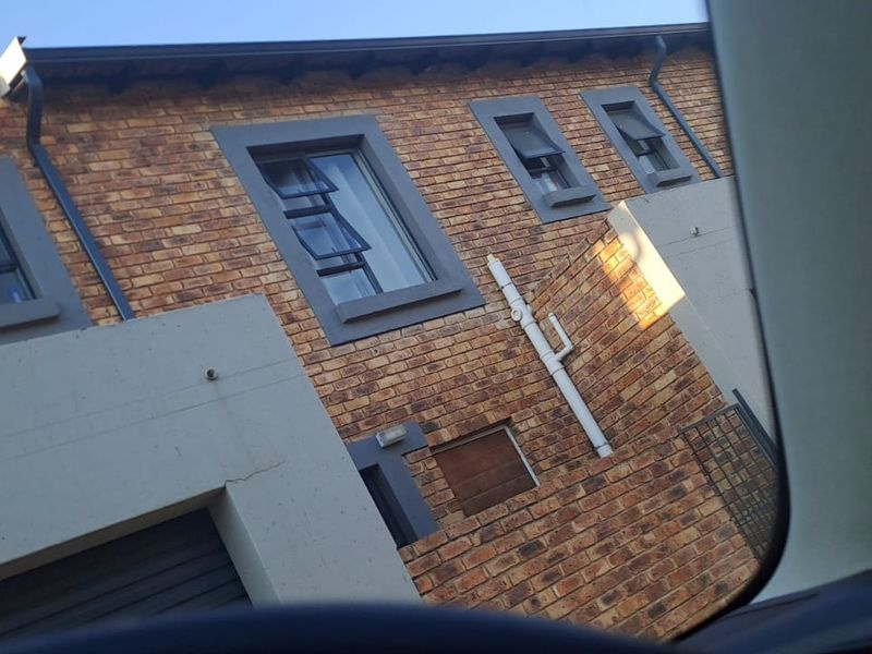 A view of the townhouse exterior featuring face brick construction, modern grey window frames, and a garage entrance.