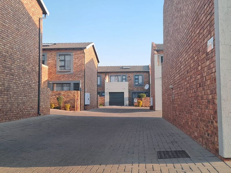 View of the townhouse complex driveway and exterior brick facades with paved access and garage entry points.