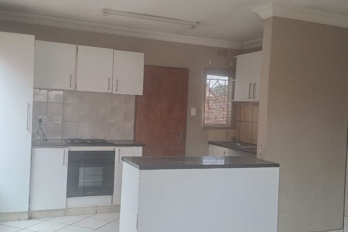 A functional kitchen featuring built-in cabinetry, a hob, an oven, and tiled flooring, offering a blank canvas for modern updates.