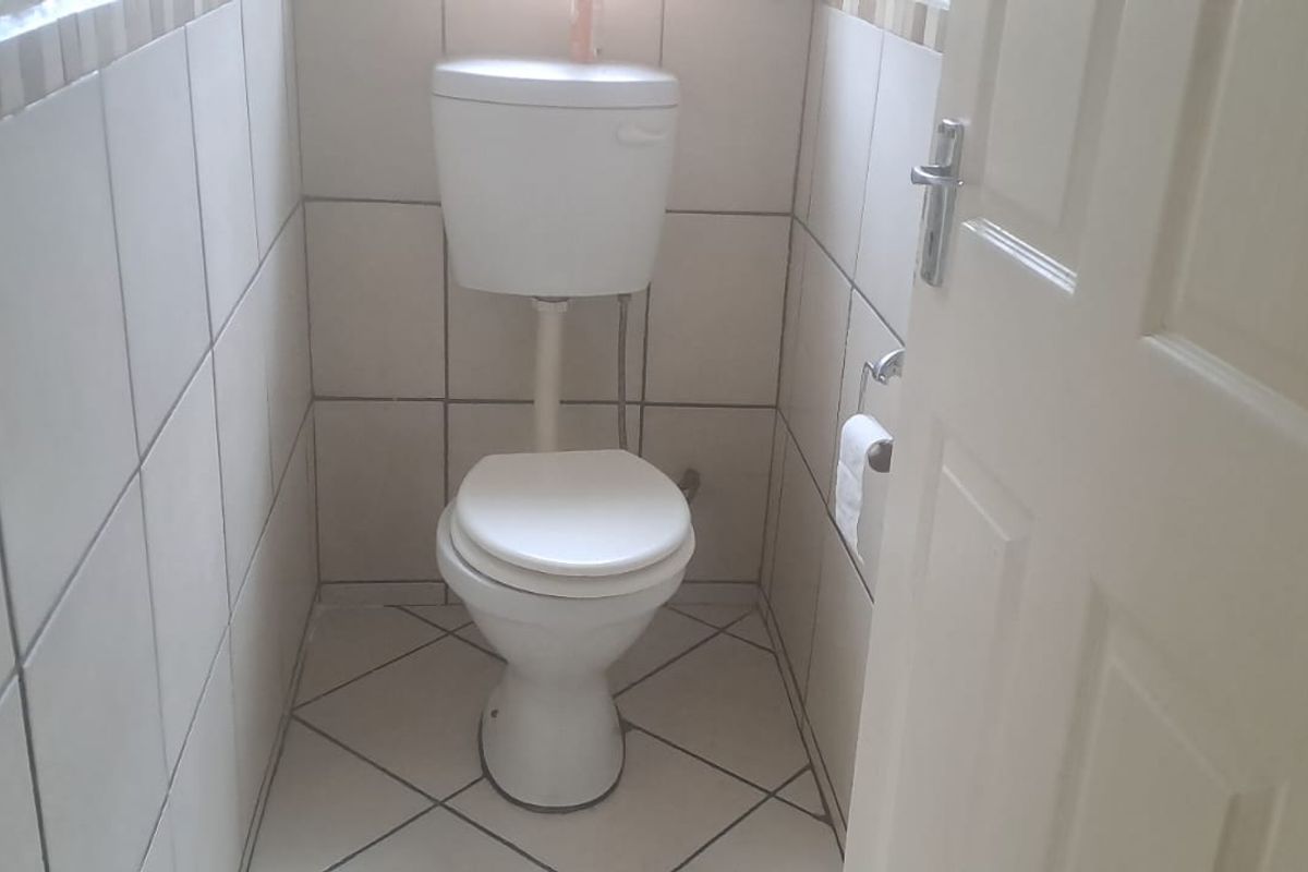 A compact, functional guest toilet featuring neutral ceramic wall and floor tiling.