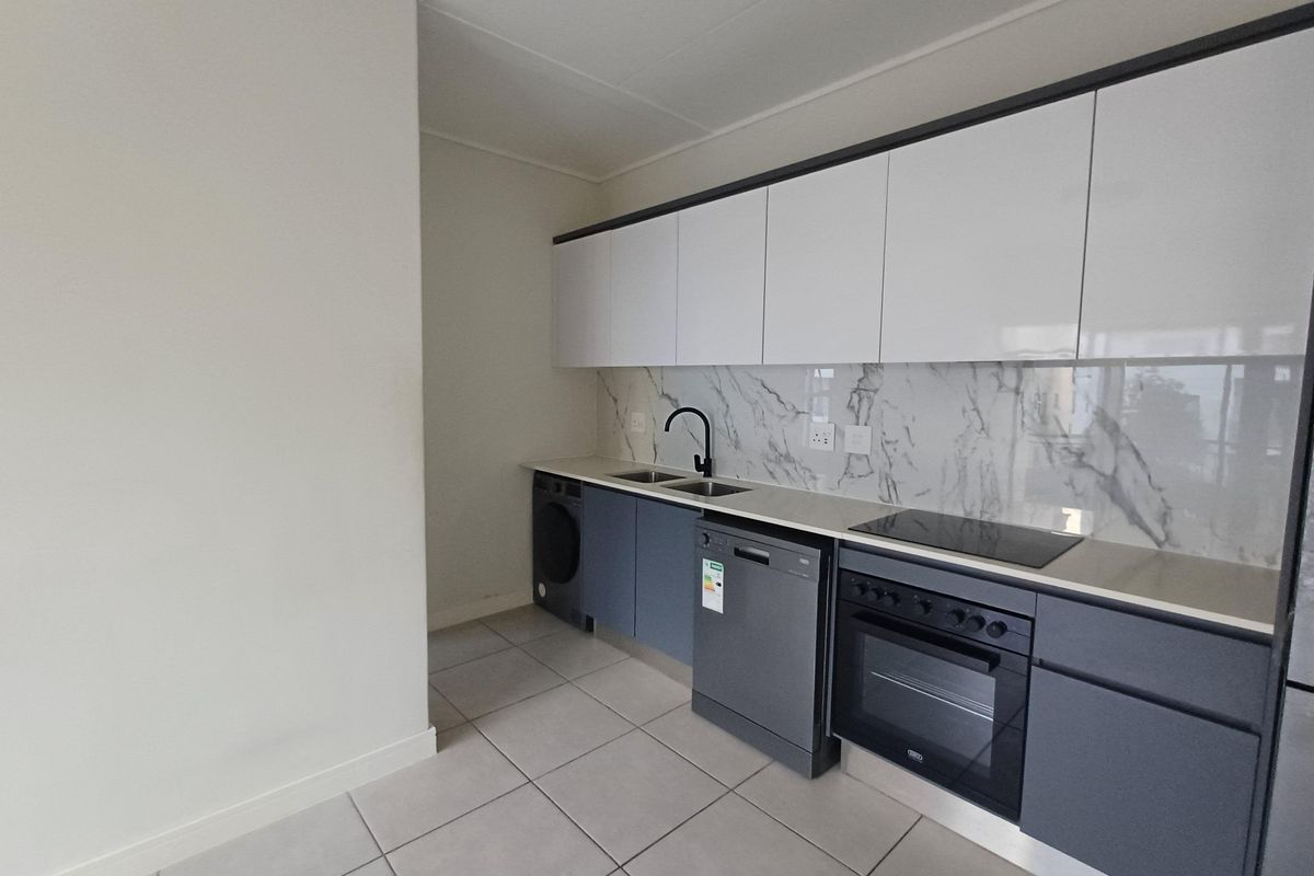 Modern kitchen featuring sleek dark grey cabinetry, white upper cabinets, marble-look splashback, integrated oven, electric hob, and tiled flooring.