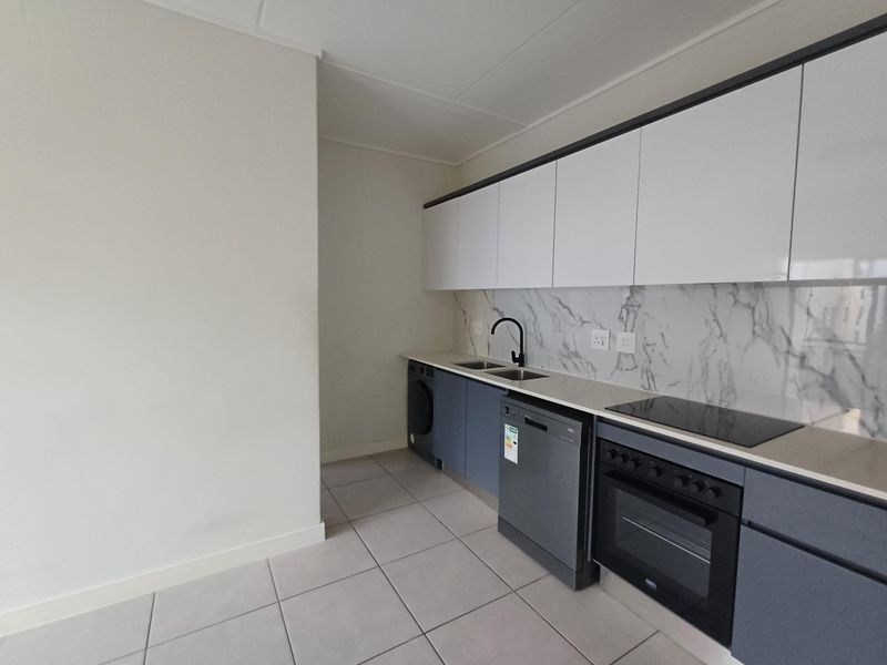 Modern kitchen featuring sleek grey and white cabinetry, marble-effect splashback, integrated oven, hob, and double sink with tiled flooring.
