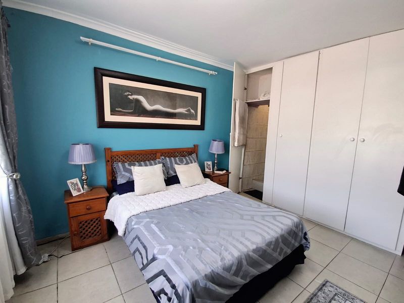 A bedroom featuring tiled flooring, built-in cupboards, and a blue accent wall, offering a functional space with potential for modern updates.