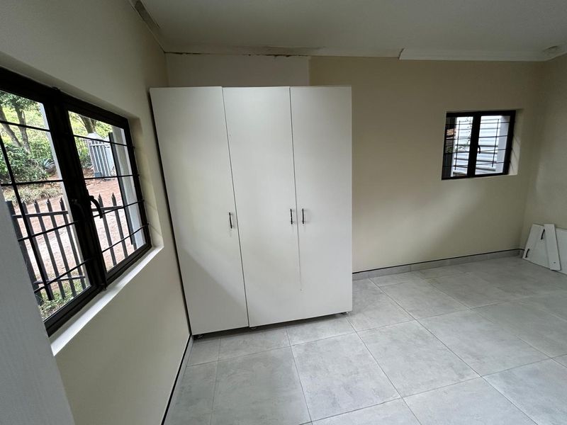 A bedroom featuring tiled flooring, built-in wardrobe, and security bars on the windows. The room requires minor cosmetic repairs to the ceiling.
