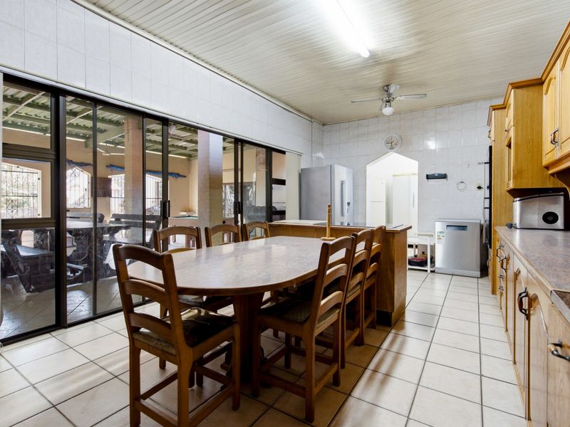 Open plan kitchen and dining area featuring timber cabinetry, tiled flooring, and large sliding glass doors providing seamless access to the outdoor patio.