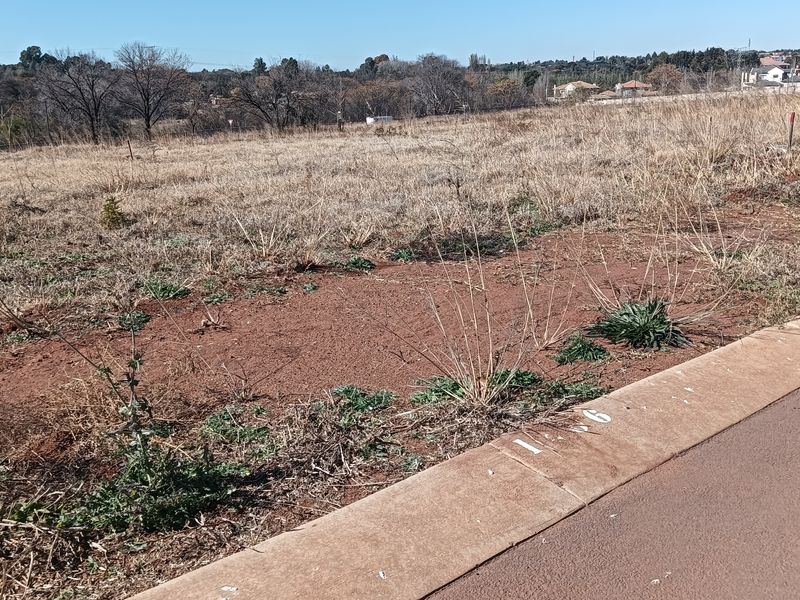 A view of a vacant residential plot featuring a concrete curb and utility box, ready for development.