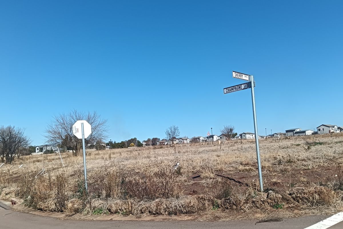A street corner view of a vacant residential plot featuring street signage at the intersection of Sherry Crescent and Champagne Street.