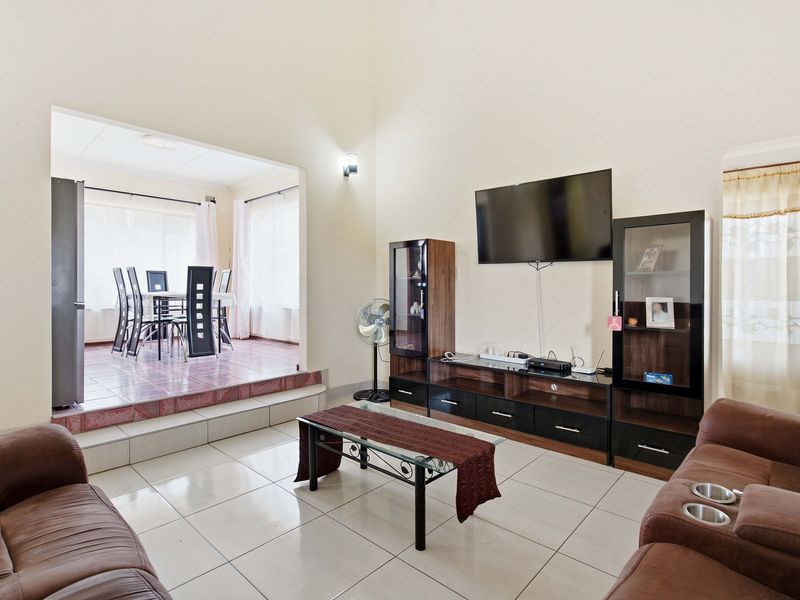 Open plan living area featuring tiled floors and a raised dining space, providing a functional layout with integrated storage cabinetry.