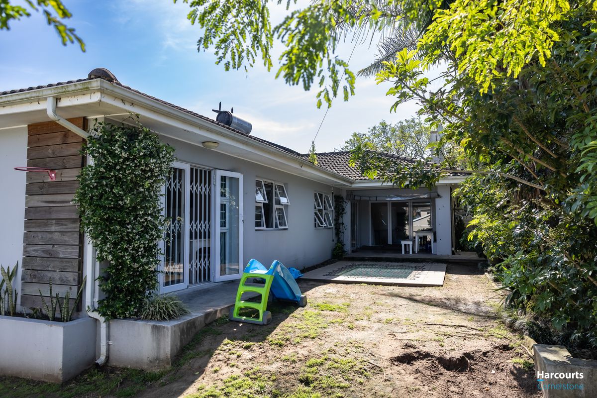 Rear exterior view of the house featuring a tiled patio area, security gates, and solar water heating system installed on the roof.