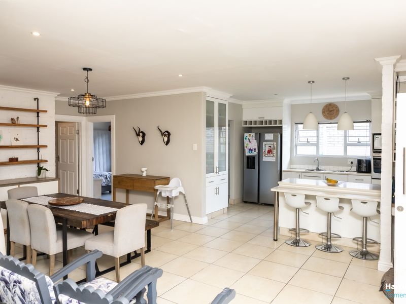 Spacious open-plan living and dining area featuring a modern kitchen with a breakfast island, tiled floors, and ample built-in cabinetry.