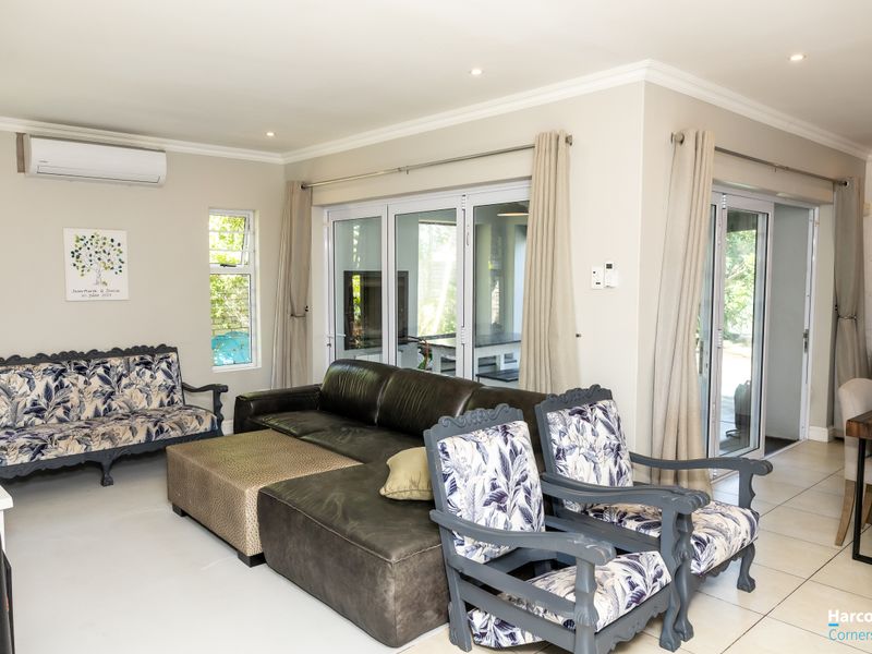 Spacious living area featuring tiled flooring, recessed downlighting, and large aluminium sliding doors providing seamless access to the outdoor patio area.