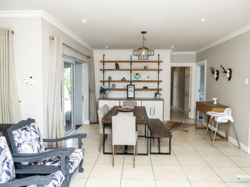 Bright dining area featuring tiled flooring, recessed lighting, and a custom built-in shelving unit with direct access to the outdoor patio through sliding doors.