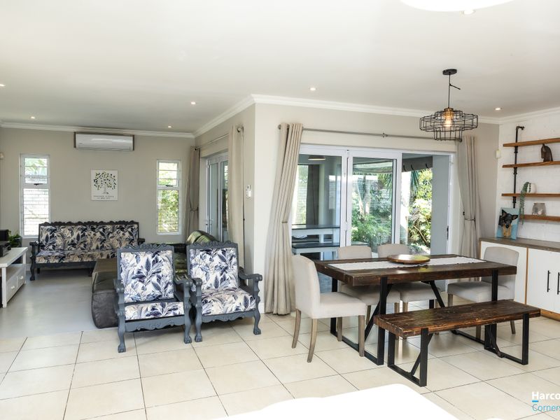 Spacious open-plan living and dining area featuring tiled floors, recessed lighting, and large sliding glass doors providing seamless access to the outdoor patio.