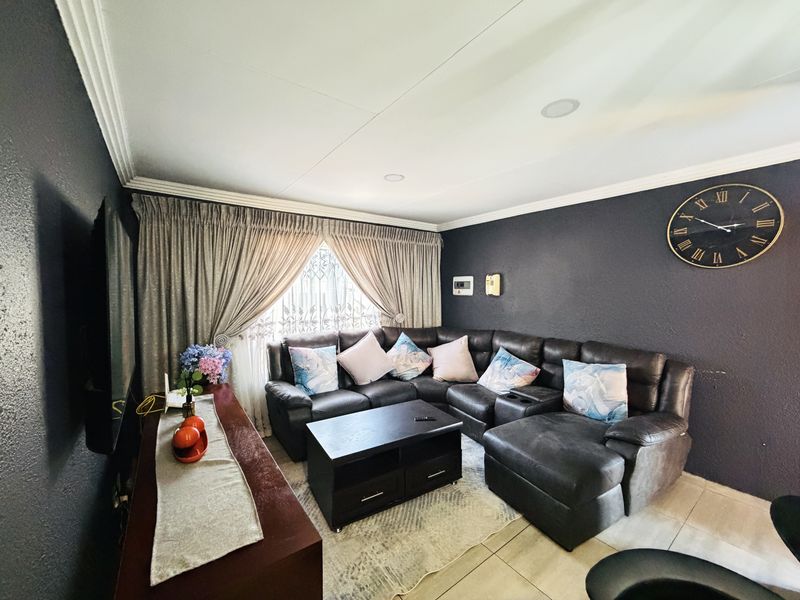 A living room featuring dark accent walls, tiled flooring, recessed ceiling lighting, and decorative crown molding.