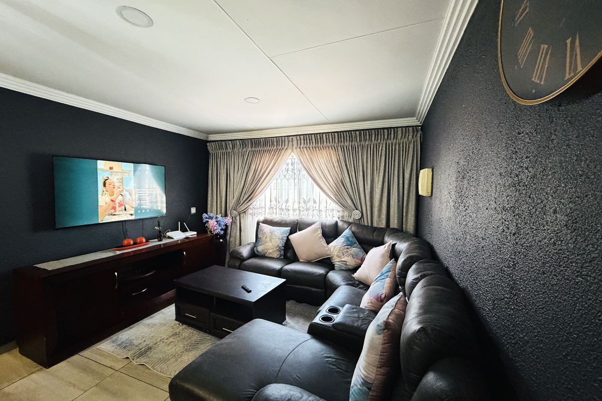 A cozy living room featuring dark textured walls, crown molding, recessed lighting, and tiled flooring, creating a comfortable and intimate entertainment space.